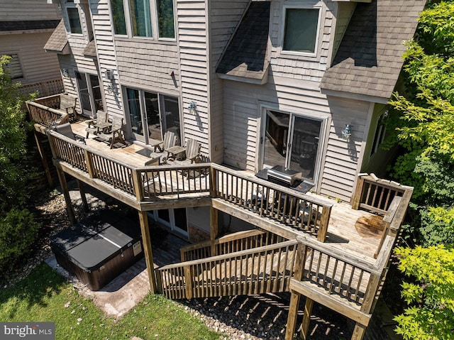 rear view of house with a wooden deck and a hot tub