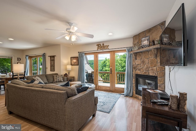 living room featuring a fireplace, light wood-type flooring, a wealth of natural light, and ceiling fan