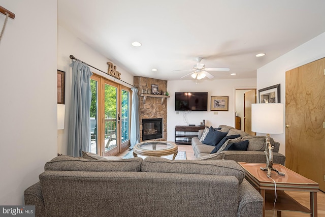 living room featuring a stone fireplace, ceiling fan, and hardwood / wood-style flooring