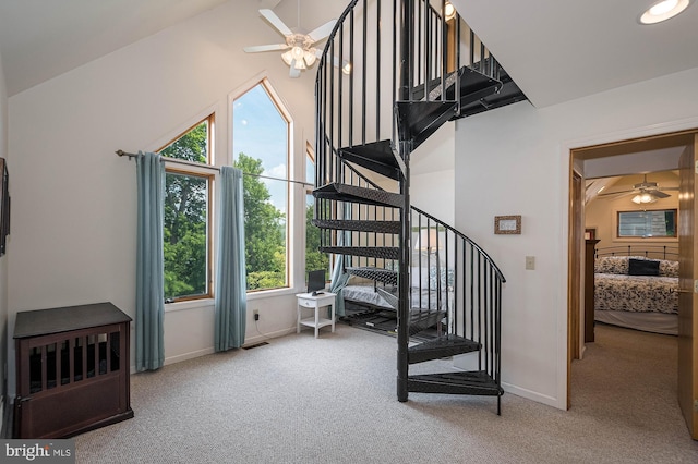 stairs with carpet flooring, high vaulted ceiling, and ceiling fan