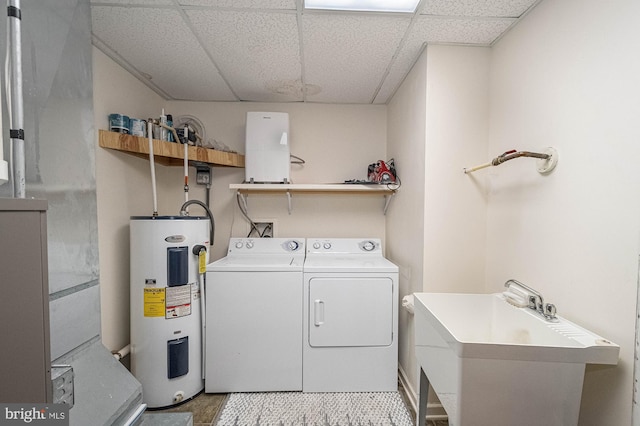 laundry area with electric water heater, washer and clothes dryer, and sink