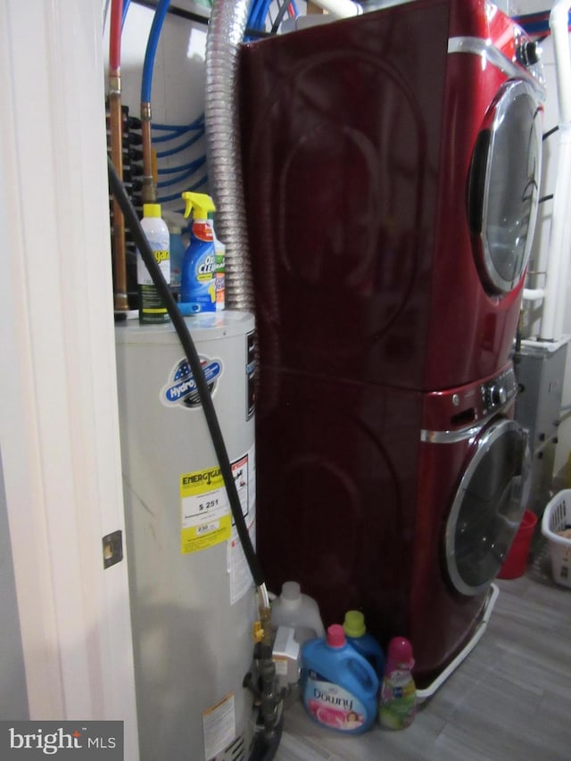 laundry area with stacked washer / dryer, wood-type flooring, and water heater