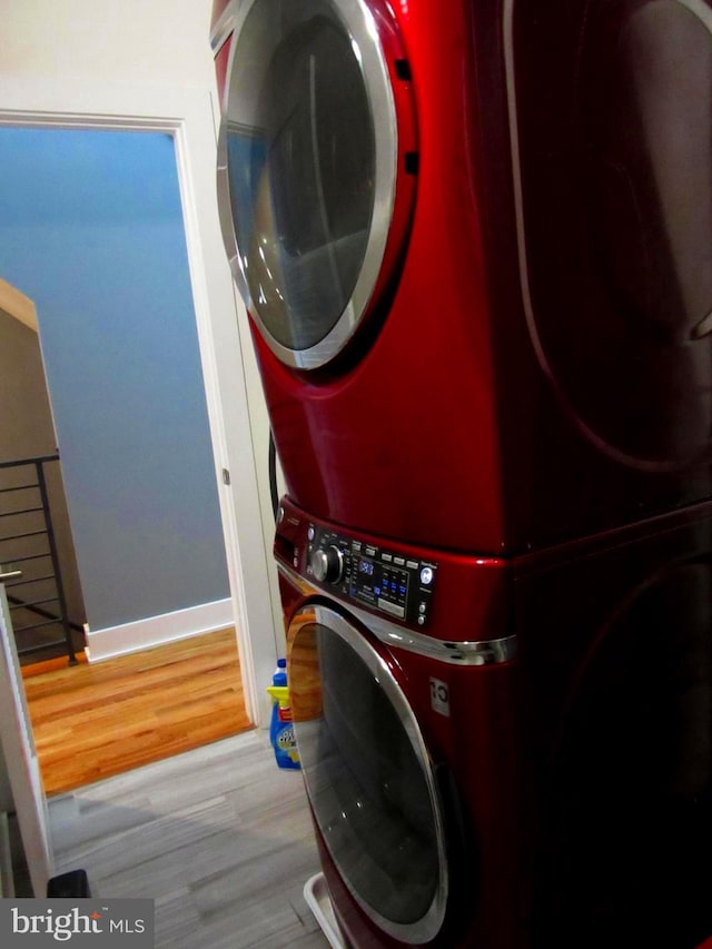 laundry room with hardwood / wood-style flooring and stacked washing maching and dryer