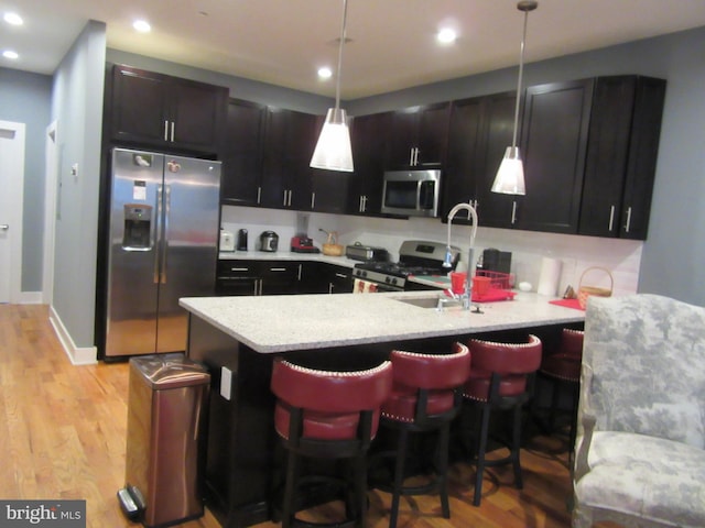 kitchen featuring stainless steel appliances, light wood-type flooring, and a kitchen bar