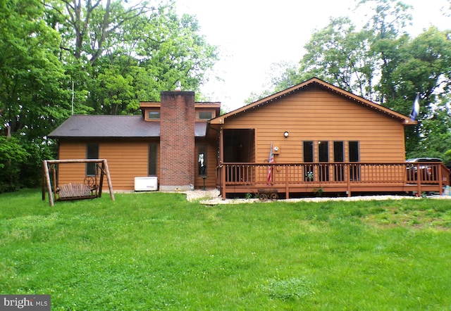 back of property with a deck and a lawn