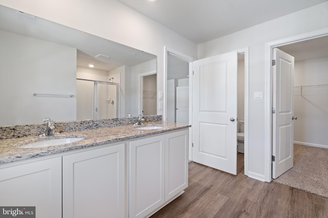 bathroom with hardwood / wood-style flooring, vanity, toilet, and walk in shower