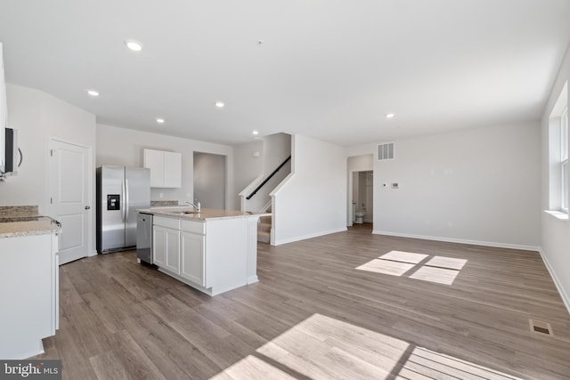 kitchen featuring white cabinets, a center island with sink, sink, light hardwood / wood-style flooring, and appliances with stainless steel finishes