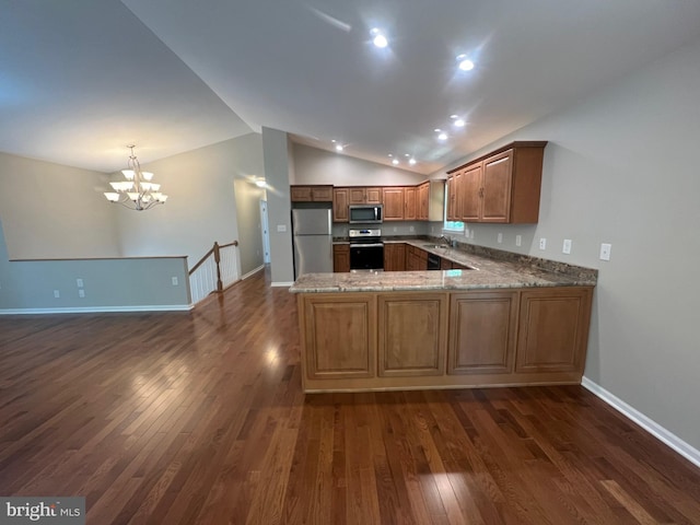 kitchen featuring kitchen peninsula, stainless steel appliances, vaulted ceiling, dark wood-type flooring, and an inviting chandelier