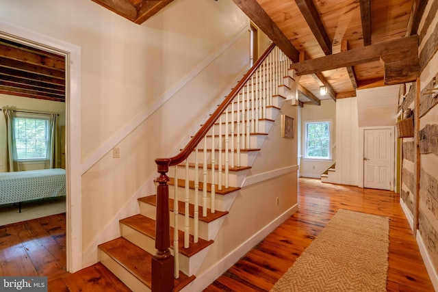 stairs with lofted ceiling with beams, wooden ceiling, and wood-type flooring