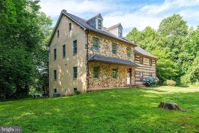 back of house with cooling unit and a lawn