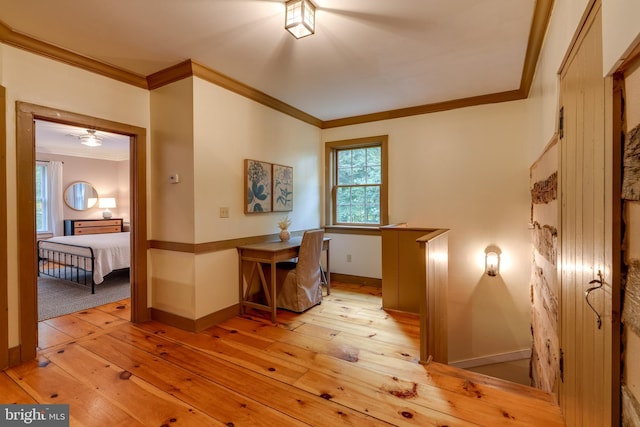 unfurnished office featuring light hardwood / wood-style floors, ceiling fan, and crown molding