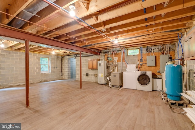 basement featuring washer and clothes dryer, light hardwood / wood-style flooring, electric panel, and water heater