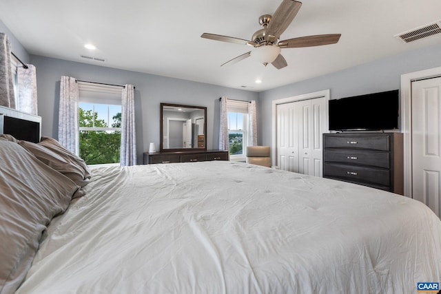 bedroom featuring multiple windows, ceiling fan, and multiple closets