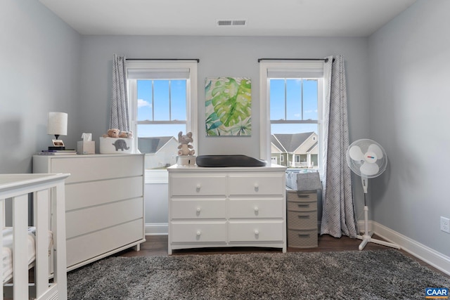 bedroom with multiple windows and dark hardwood / wood-style floors