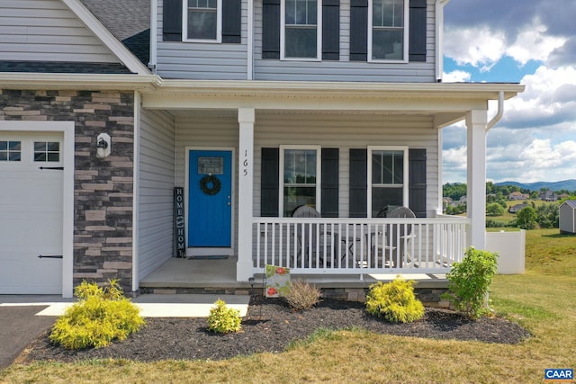 view of exterior entry with covered porch and a garage