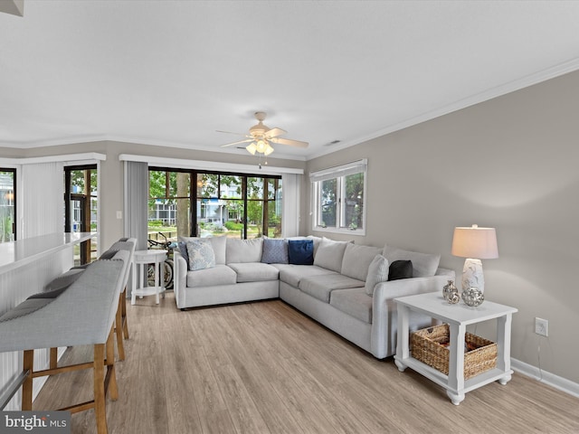 living room with light wood-type flooring, plenty of natural light, ornamental molding, and ceiling fan