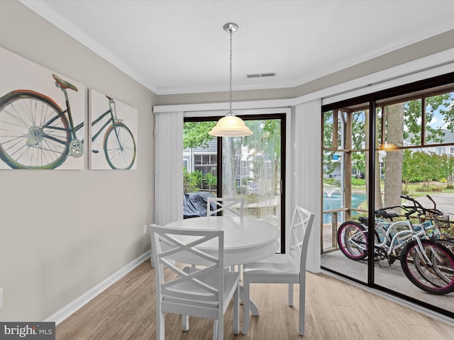 dining space featuring light wood-type flooring and ornamental molding