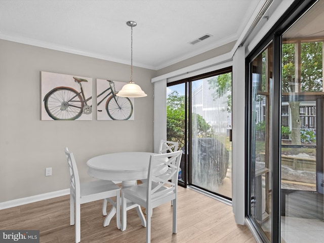 dining room with crown molding and light wood-type flooring