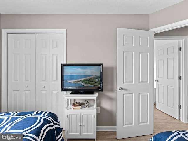 bedroom with light hardwood / wood-style floors and a closet