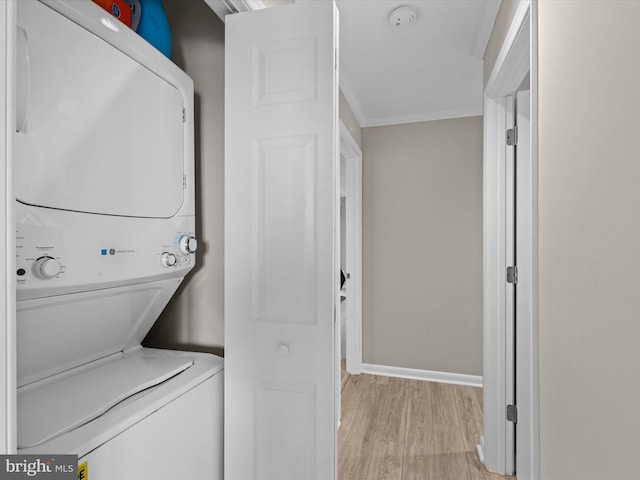 laundry room featuring crown molding, light hardwood / wood-style floors, and stacked washer / drying machine