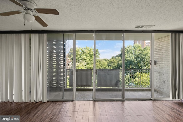 doorway featuring wood-type flooring, a textured ceiling, and ceiling fan