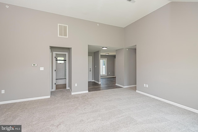 carpeted empty room featuring high vaulted ceiling