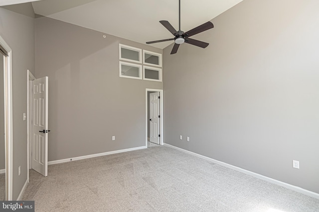 carpeted spare room featuring ceiling fan and a towering ceiling