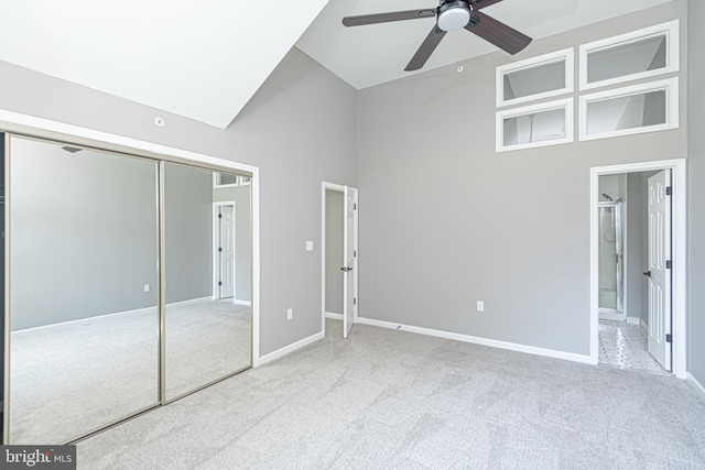 unfurnished bedroom with ceiling fan, light colored carpet, high vaulted ceiling, and a closet