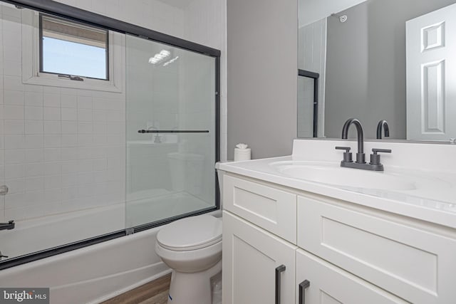 full bathroom featuring vanity, shower / bath combination with glass door, toilet, and wood-type flooring