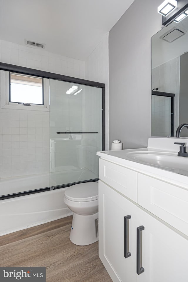 full bathroom with toilet, vanity, combined bath / shower with glass door, and hardwood / wood-style flooring