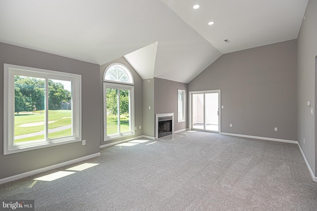 unfurnished living room featuring a high end fireplace, light colored carpet, vaulted ceiling, and plenty of natural light