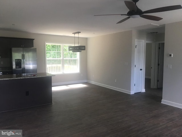 interior space with stainless steel refrigerator with ice dispenser, dark wood-type flooring, decorative light fixtures, ceiling fan, and light stone countertops