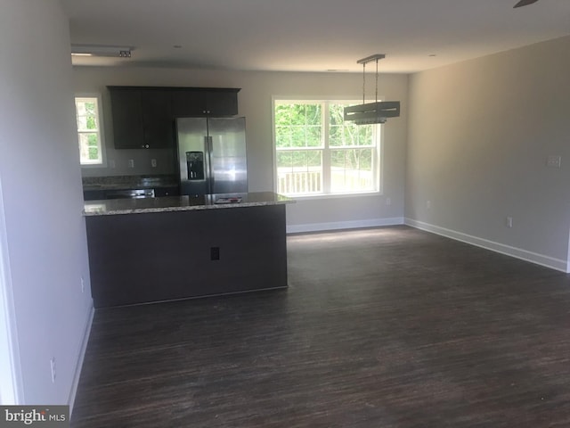 kitchen with stainless steel refrigerator with ice dispenser, light stone countertops, plenty of natural light, and pendant lighting