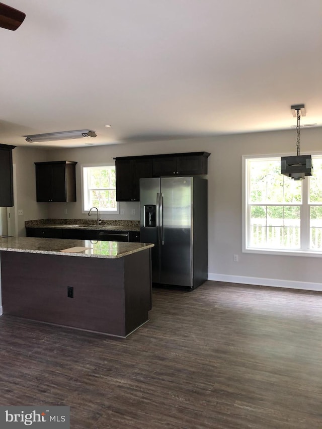 kitchen with light stone countertops, sink, dark wood-type flooring, and stainless steel fridge