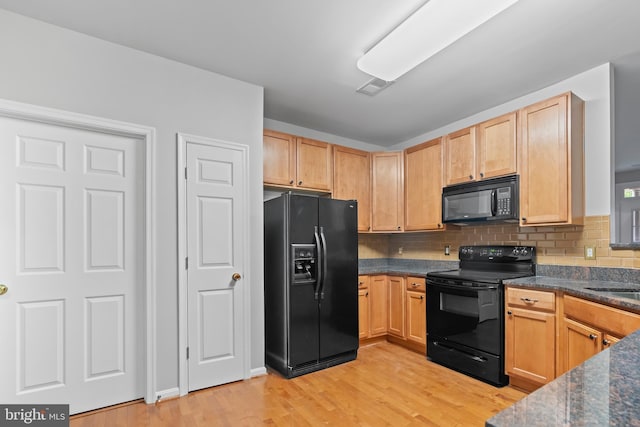 kitchen with tasteful backsplash, black appliances, light brown cabinets, light hardwood / wood-style flooring, and dark stone countertops