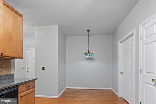 kitchen with pendant lighting, dark stone counters, light hardwood / wood-style flooring, decorative backsplash, and black dishwasher