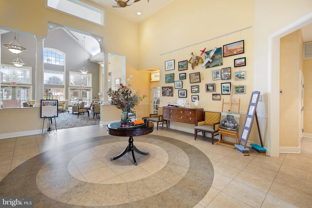 living area featuring light tile patterned floors, a high ceiling, and decorative columns