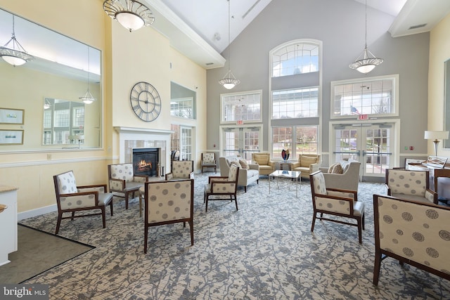 carpeted living room with a towering ceiling, a tile fireplace, and french doors