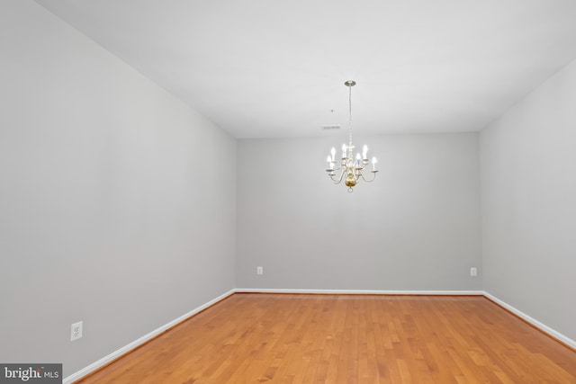 spare room with light hardwood / wood-style flooring and a notable chandelier