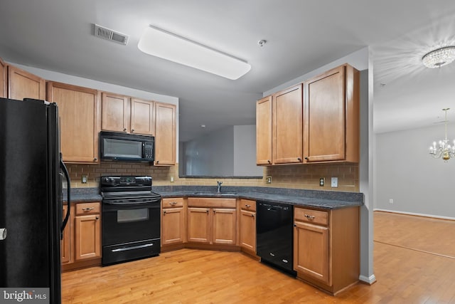 kitchen with sink, light hardwood / wood-style flooring, a notable chandelier, decorative backsplash, and black appliances