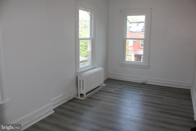 unfurnished room with dark hardwood / wood-style flooring and radiator