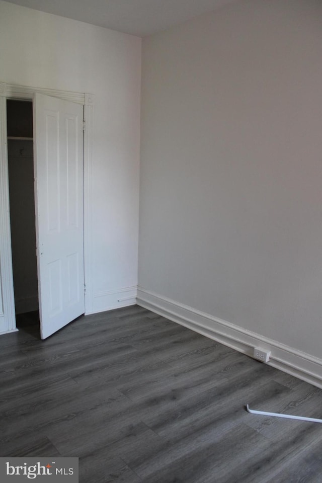 unfurnished bedroom with dark hardwood / wood-style floors and a closet