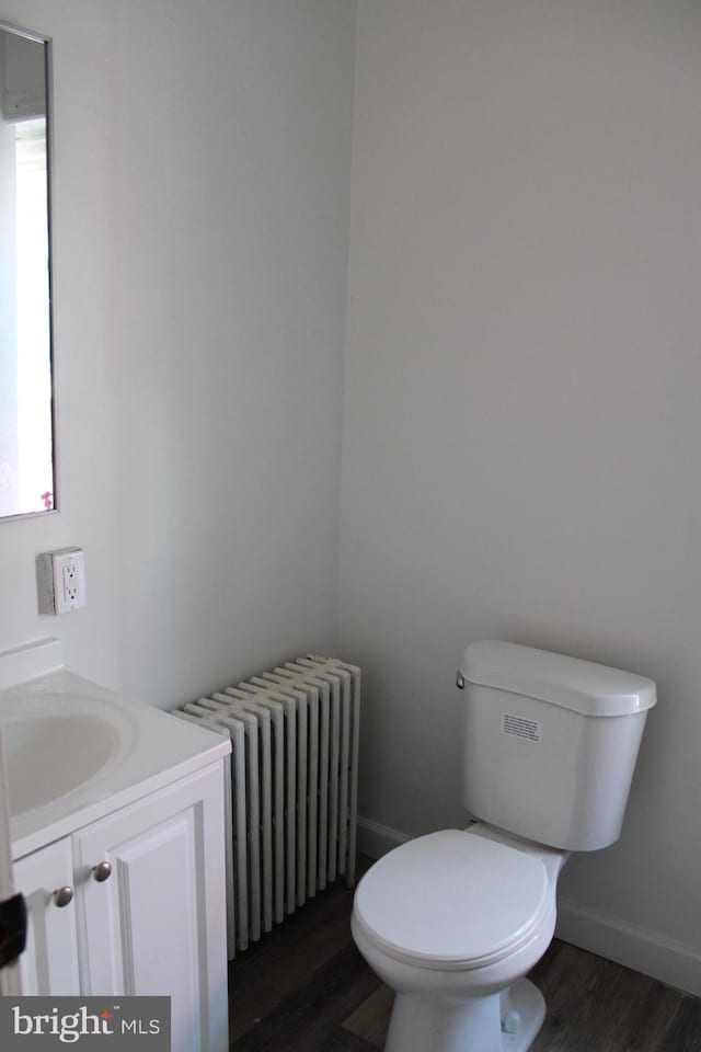 bathroom with radiator heating unit, vanity, hardwood / wood-style floors, and toilet