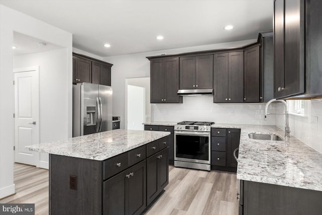 kitchen featuring sink, stainless steel appliances, tasteful backsplash, light hardwood / wood-style flooring, and a kitchen island