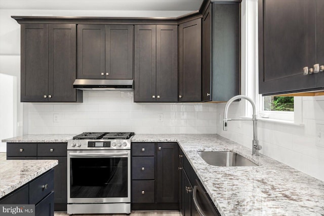 kitchen featuring light stone countertops, backsplash, dark brown cabinets, stainless steel appliances, and sink