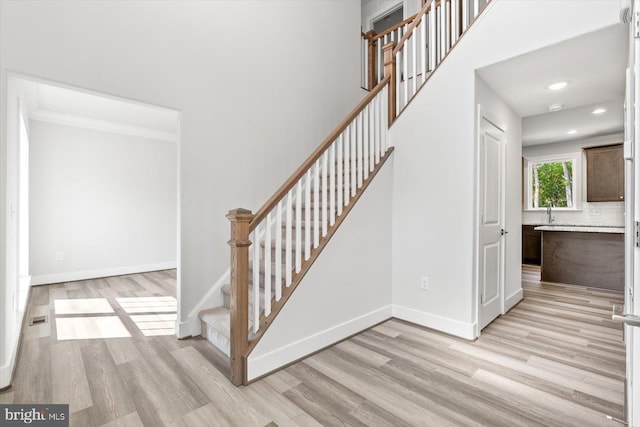 staircase with hardwood / wood-style floors and sink