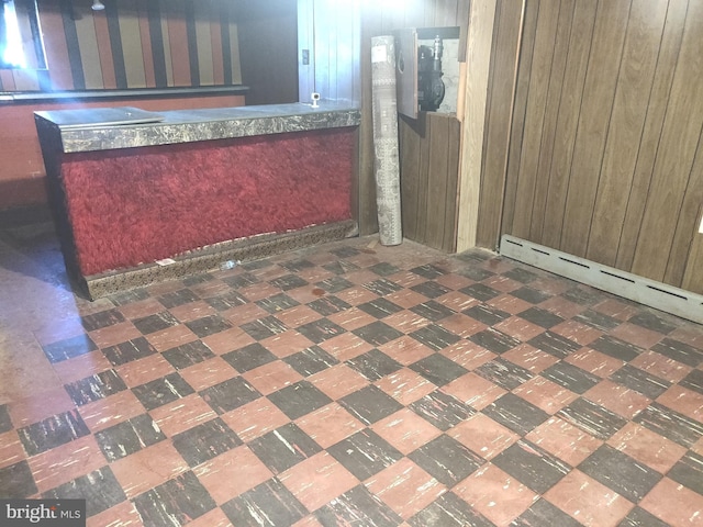 interior space with wood walls, a baseboard radiator, and indoor bar