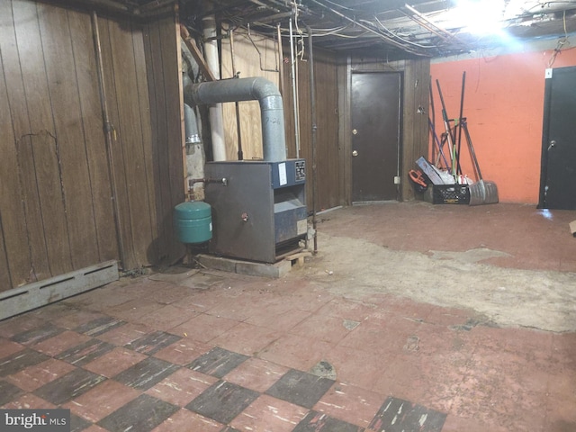 basement featuring wooden walls and a baseboard radiator