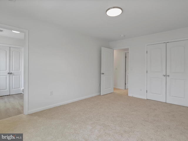 unfurnished bedroom featuring light colored carpet, baseboards, and a closet
