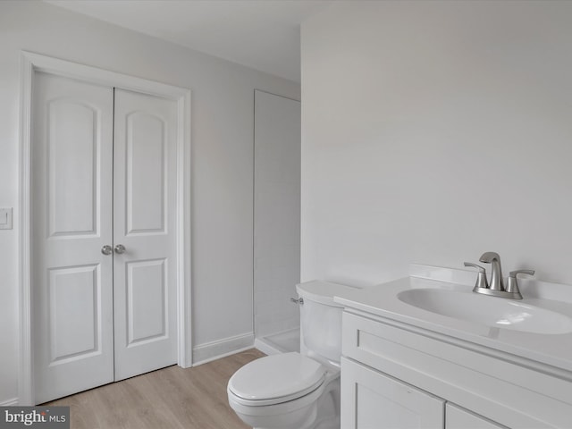 full bathroom featuring toilet, wood finished floors, vanity, and a shower